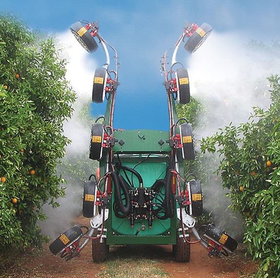 Equipment spraying rows of trees in orchard